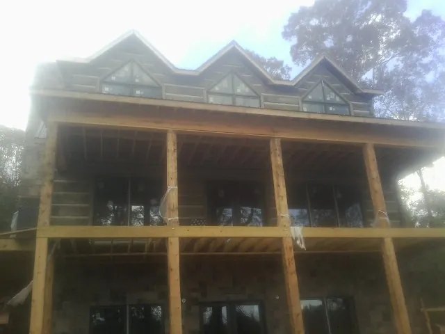 Dormers and porch framing on a large log home under construction — Roof Coating work by our crew in Oxford