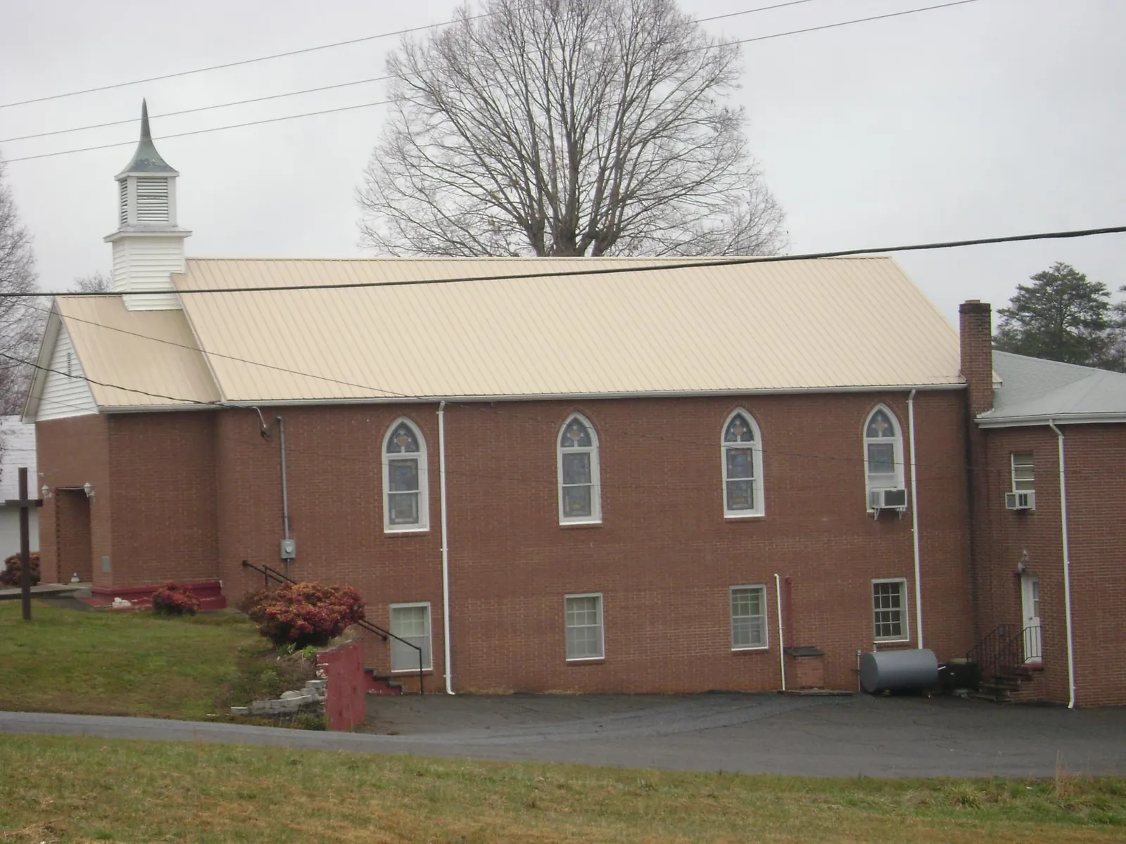 New tan metal roof on a brick church with a white steeple in Oxford